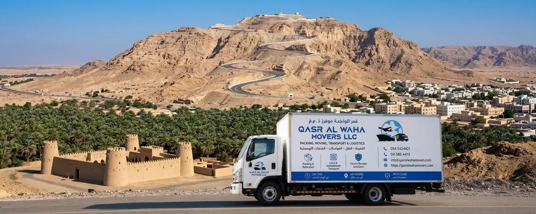 A Qasr Al Waha Movers truck below Jebel Hafeet in Al Ain, with a mud-brick fort and palm groves