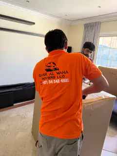 A mover beside packed cartons in a villa room