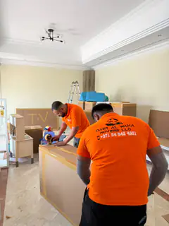 Two movers sealing cartons in a villa