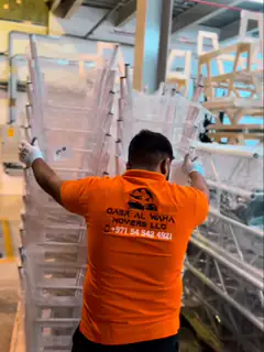 Two movers wrapping a tall flat panel in protective film
