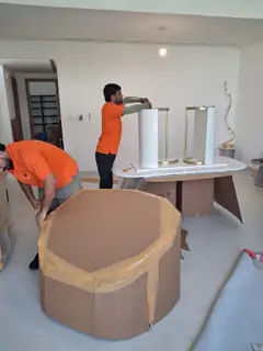 A mover wrapping a tall cylindrical item in film
