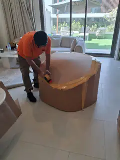 A mover taping a large round wrapped item in a villa