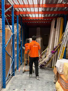 A mover wheeling a trolley down a warehouse aisle