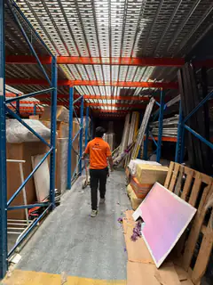 A mover walking a warehouse aisle past stored consignments