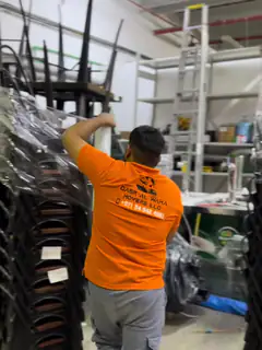 A mover steadying wrapped furniture stacked in the warehouse