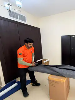 Two movers rolling and carrying a carpet out of an apartment