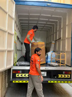 Movers loading cartons into a container at the loading bay