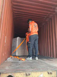 A mover strapping a wrapped item inside a container