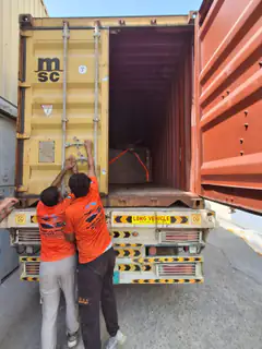 Two movers working at the rear doors of a container