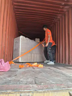 A mover tensioning orange straps across a load inside a container