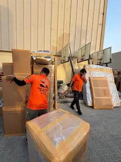 A mover carrying a large flat wrapped panel outdoors