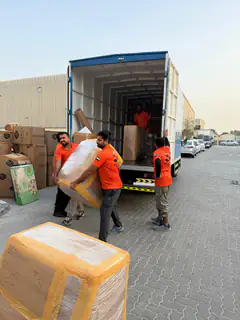Two movers loading a wrapped mattress into a truck