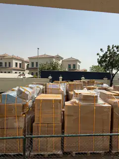 Wrapped and strapped cartons staged outside a villa