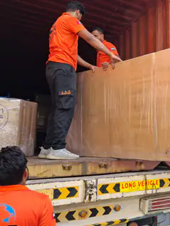 Movers passing a large wrapped panel into a container