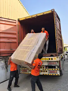 A mover loading a wrapped mattress into a container