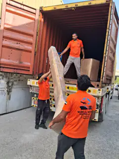 Movers lifting a large wrapped panel into a container
