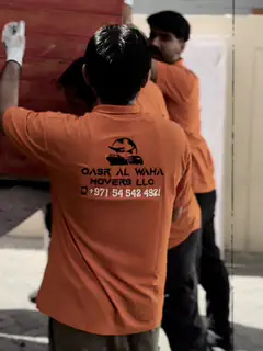 Two movers working together on a large wrapped flat item