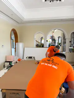 A mover packing furniture in a villa living room with arched doorways