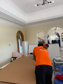 Two movers wrapping furniture in a villa reception room